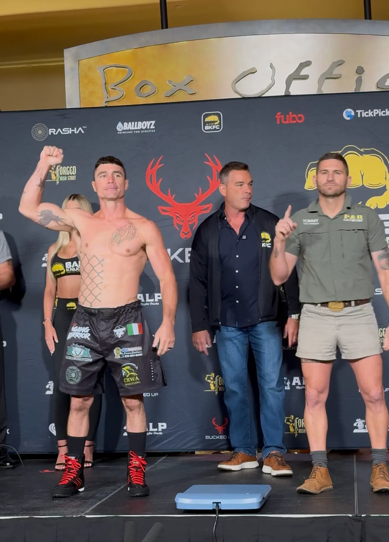 Joey Gambino flexing on stage across from his opponent at the BKFC weigh-in
